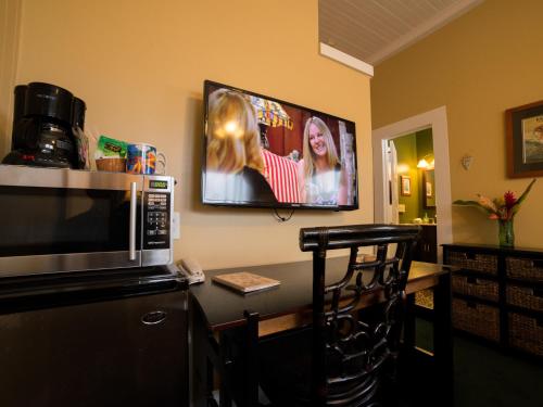 a kitchen with a microwave and a tv on the wall at Wailuku Guesthouse in Wailuku