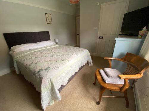a bedroom with a bed and a wooden chair and a chair at St Jude's Bed & Breakfast in Dersingham
