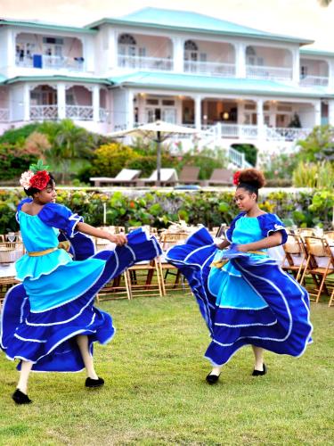 two women in blue dresses dancing in the grass at Hotel Villa Serena in Las Galeras