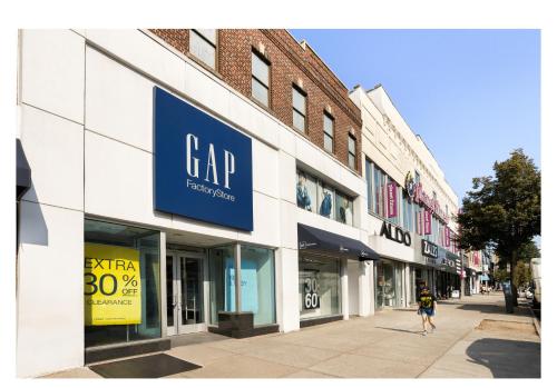 a woman walking down a sidewalk in front of a car store at avid hotels - Brooklyn Dyker Heights by IHG in Brooklyn