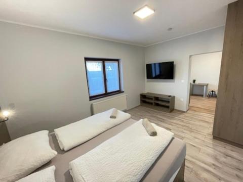 a room with two beds and a flat screen tv at Kukorica Csárda Apartman 2 in Balatonújlak