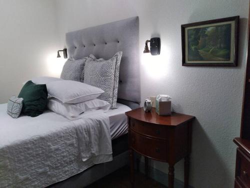 a bedroom with a bed with a wooden nightstand and a bed with pillows at Cozy Getaway in Lincoln! 
