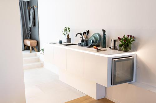 a white kitchen with a tv on a wall at geislerAPPARTMENTS in Gramatneusiedl