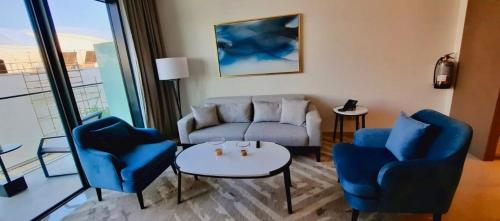a living room with a couch and two chairs and a table at شقق فندقية خاصة في منتجع العنوان الشاطئي - مراسي البحرين in Rayyā