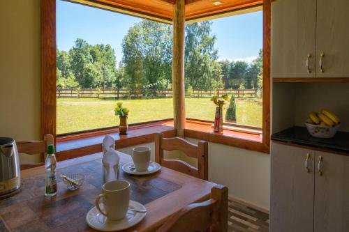 a kitchen with a table and a large window at Cabaña Alto Arrayán in Pucón