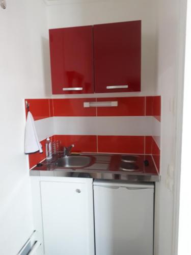 a kitchen with red cabinets and a sink at STUDIO D'OLIVE in Châteauroux