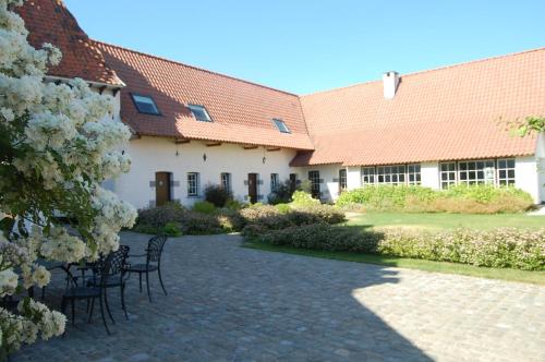 un cortile di un edificio con sedie e fiori di Ferme Delgueule a Tournai