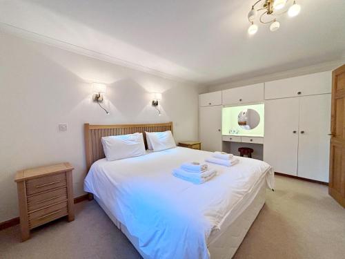 a bedroom with a white bed with towels on it at Fisher chalet in Crianlarich