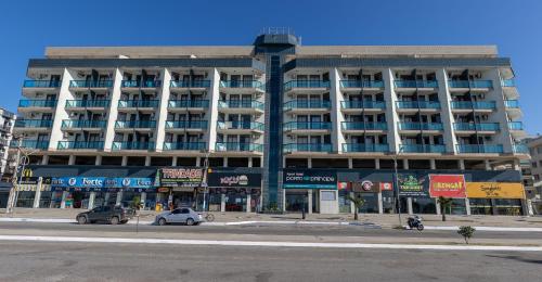 a large building with cars parked in front of it at Apart Hotel Porto Príncipe in Cabo Frio