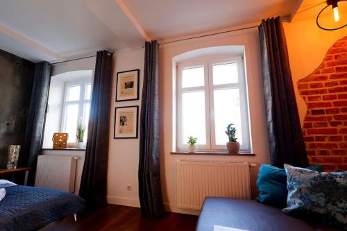 una camera da letto con due finestre, un letto e un divano di Przytulnie z The GG Apartments a Poznań