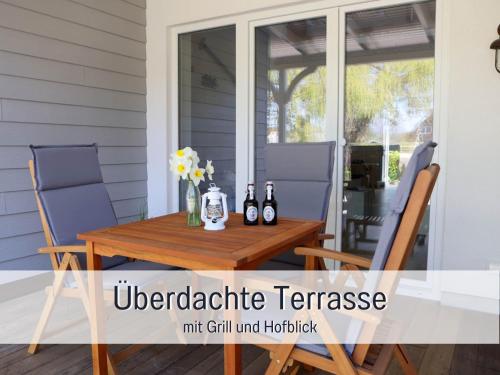 a table on a porch with two chairs and two bottles at RamosHansenHof Fewo Fördebrise mit Sauna in Steinberg