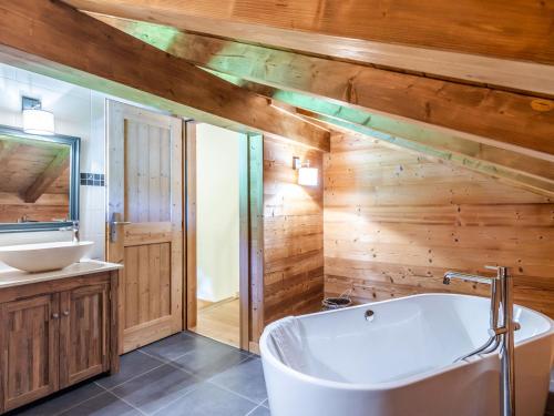La salle de bains est pourvue de murs en bois, d'une baignoire et d'un lavabo. dans l'établissement Chalet de charme, 4 chambres avec terrasse, proche centre et pistes, navette gratuite - Morzine - FR-1-754-27, à Morzine