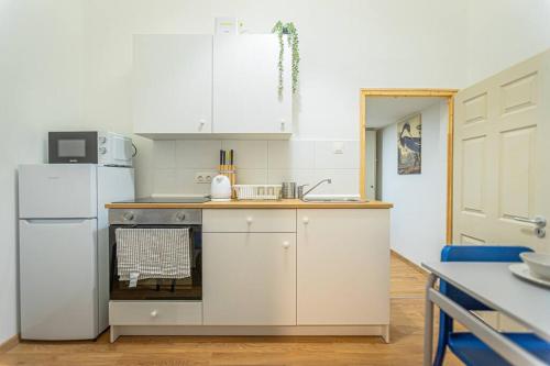 La cuisine est équipée de placards blancs et d'un réfrigérateur blanc. dans l'établissement CENTER APARTMENT BUDAPEST, Akacfa street, à Budapest