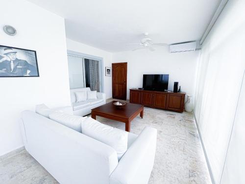 a living room with a white couch and a table at OCEANFRONT & Garden View VILLAS Hotel WIFI BBQ Parking Los Corales beach CLUB & SPA in Punta Cana