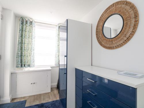 baño con espejo y tocador azul en Beach Cottage, en Redruth