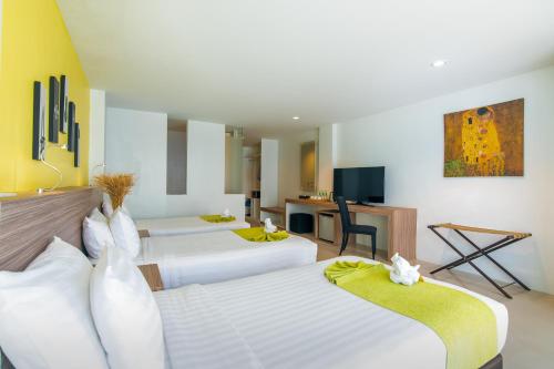a hotel room with three beds and a desk at The Lantern Resorts Patong - SHA Extra Plus in Patong Beach