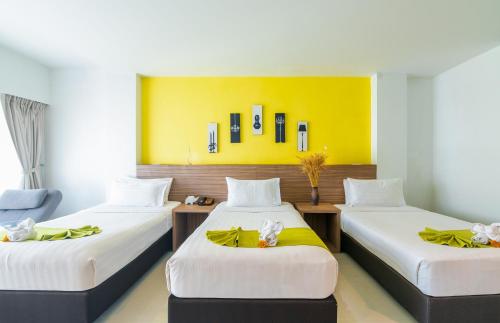 a room with two beds and a yellow wall at The Lantern Resorts Patong - SHA Extra Plus in Patong Beach