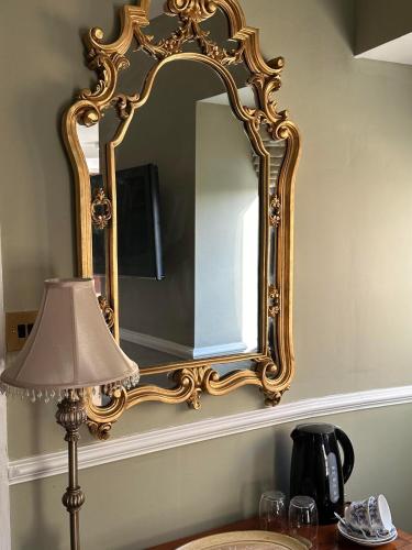 a large gold mirror on a wall with a lamp at Burford Lodge - Adults only in Burford