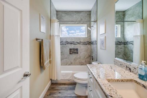 a bathroom with a toilet and a sink and a window at Spacious Home With Heated Pool! Sleeps 15! Billiard table! in Hernando Beach