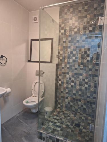 a bathroom with a toilet and a glass shower at SEA FACING modern 3-bedroom apartment, Umdloti in Umdloti