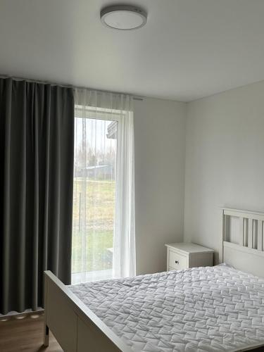 ein Schlafzimmer mit einem Bett und einem großen Fenster in der Unterkunft Marupe Saules in Mārupe