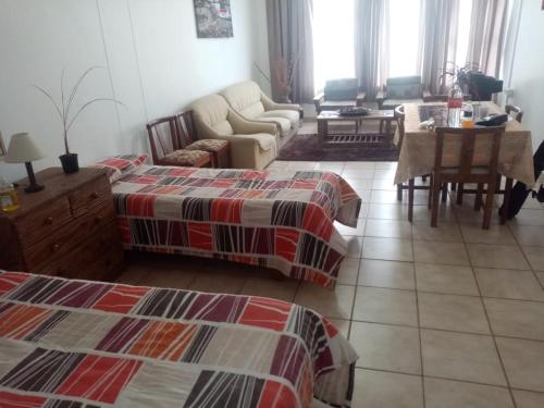 a living room with two beds and a couch and a table at Happy days in Amanzimtoti