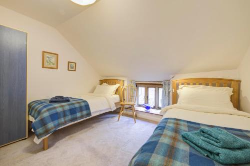 a bedroom with two beds and a chair in it at Converted stables and hayloft in former farmyard in Saint Briavels