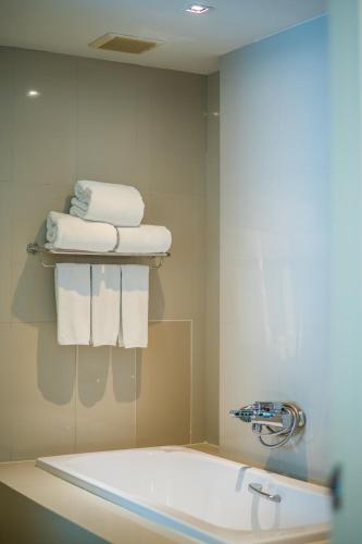 a bathroom with a bath tub and a pile of towels at The Lantern Resorts Patong - SHA Extra Plus in Patong Beach