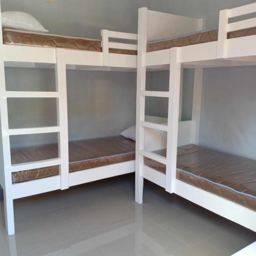 a room with white bunk beds in a room at JJP Dormitel in Molave