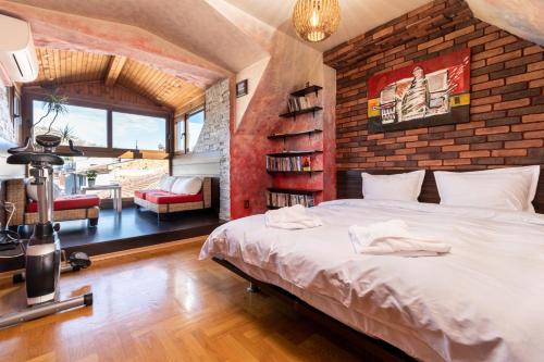 una camera con un grande letto e un muro di mattoni di Penthouse Tepeto a Plovdiv