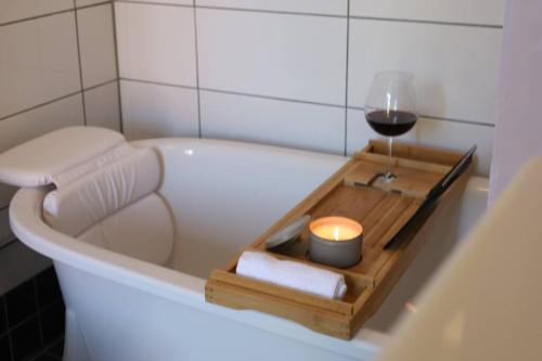 a bath tub with a glass of wine and a candle at Fully Equipped Cosy Flat Close to Malmö&Copenhagen in Vellinge