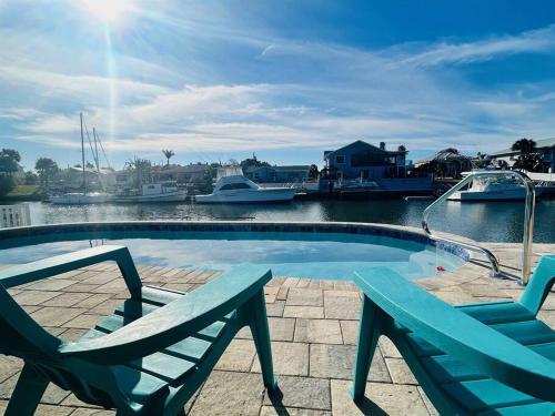 a swimming pool with two chairs and boats in the water at Waterfront home with pool and gameroom! in Hernando Beach
