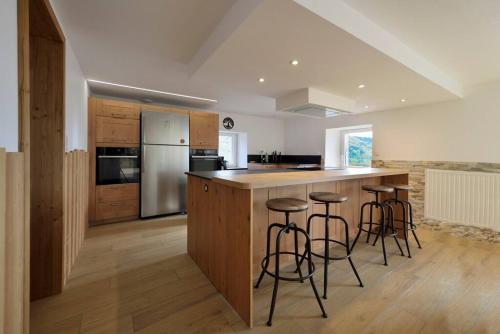 une cuisine avec un îlot et des tabourets de bar dans l'établissement Gîte la Croisée Pierre, à Saulxures-sur-Moselotte