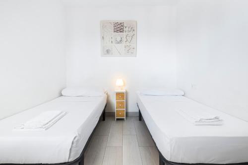ベニドルムにあるAcuarium 3-19-E Apartment Levante Beachの白い壁とウッドフロアの客室で、ベッド2台が備わります。