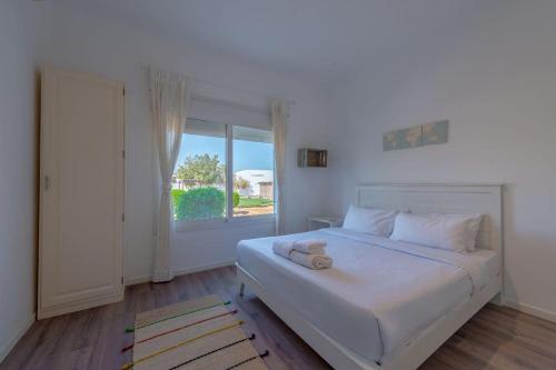 ein weißes Schlafzimmer mit einem großen Bett und einem Fenster in der Unterkunft unique flat_ garden and lagoon in Hurghada