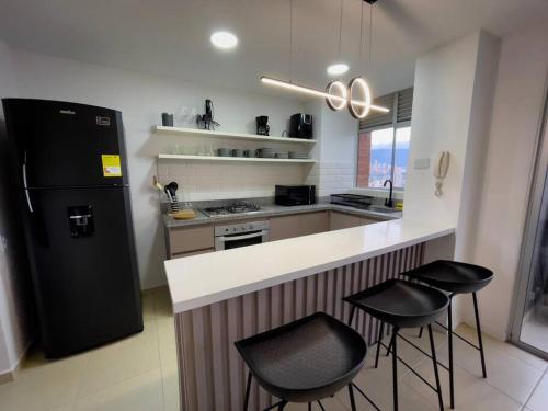 a kitchen with a black refrigerator and two bar stools at Luxury, 2 Bdr, Pv Balconie, Top View El Poblado in Medellín