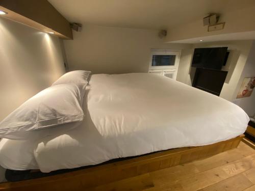 uma cama com lençóis brancos e almofadas num quarto em MILANO 11 em Arona