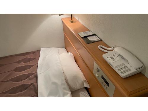 um telefone sentado numa cómoda ao lado de uma cama em Hotel Sunroute Patio Goshogawara - Vacation STAY 30370v em Goshogawara