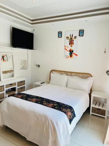 a bedroom with a white bed and a tv on the wall at African Haven Guest House in Cape Town