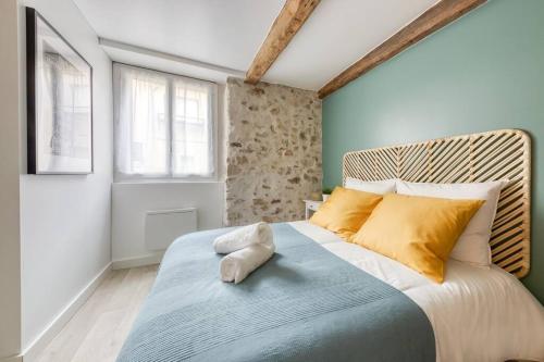 - une chambre avec un grand lit et des oreillers jaunes dans l'établissement Le Refuge, T2 élégant Aéroport d'Orly, à Athis-Mons