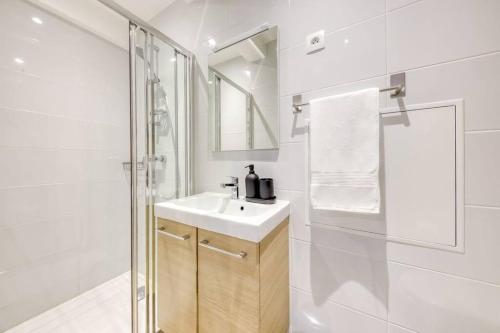 La salle de bains blanche est pourvue d'un lavabo et d'une douche. dans l'établissement Le Refuge, T2 élégant Aéroport d'Orly, à Athis-Mons