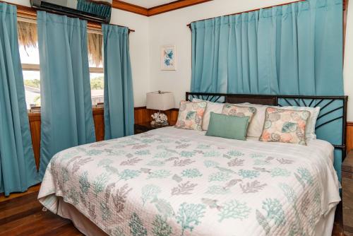 sypialnia z dużym łóżkiem z niebieskimi zasłonami w obiekcie Dolphin Dreams Villa B3 w mieście San Pedro