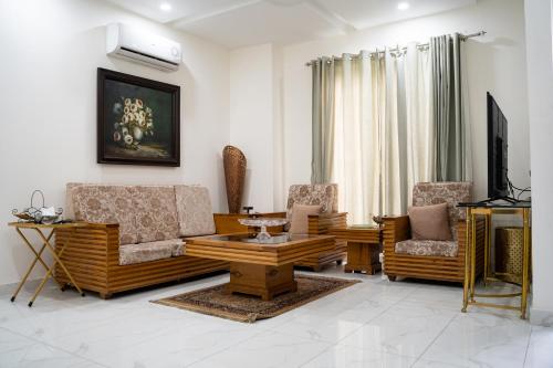uma sala de estar com um sofá, cadeiras e uma mesa em Gulberg Luxe Living 2-BR Apartment em Lahore