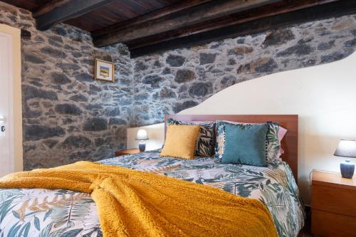 1 dormitorio con 1 cama con pared de piedra en Casa da Vizinha, en Ponta do Sol