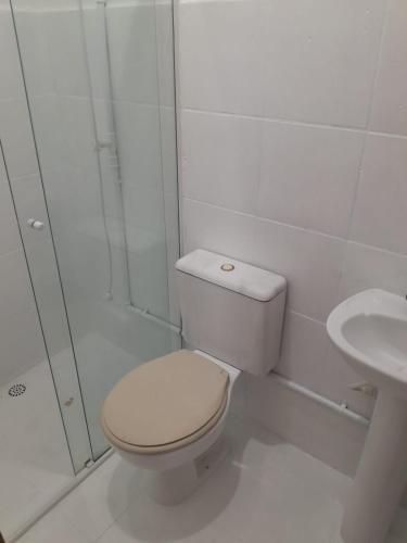 a white bathroom with a toilet and a sink at Itapira Flats - Apto 7 in Imbituba