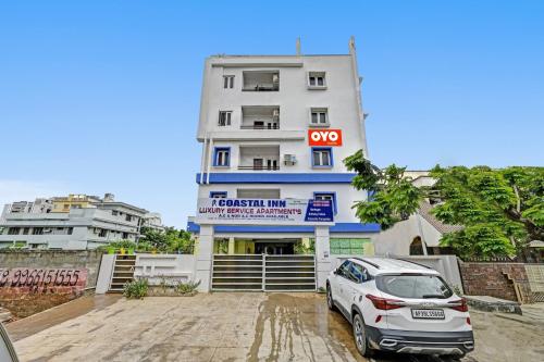 une voiture blanche garée devant un bâtiment dans l'établissement OYO Coastal Inn Luxury Service Apartments, à Kakinada