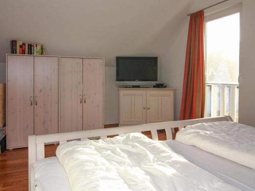 a bedroom with a bed and a flat screen tv at Doppelhaushälfte Dünenrose, Glowe in Glowe