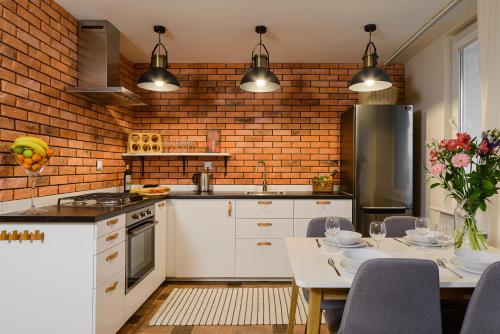 a kitchen with white cabinets and a brick wall at P&O Apartments Hawajska in Warsaw