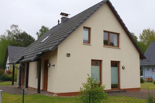 een wit huis met een zwart dak bij Karlshagen, Ferienhaus am Hasenwinkel in Ostseebad Karlshagen