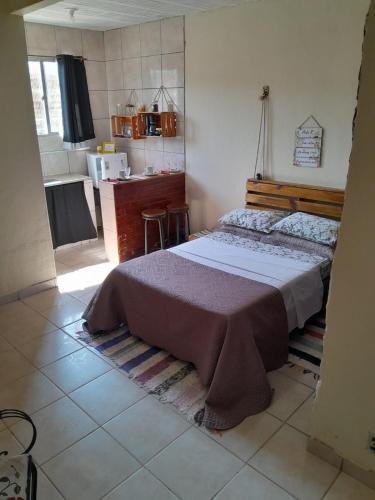 sypialnia z dużym łóżkiem i kuchnią w obiekcie Suíte Estação da Paz w mieście Miguel Pereira
